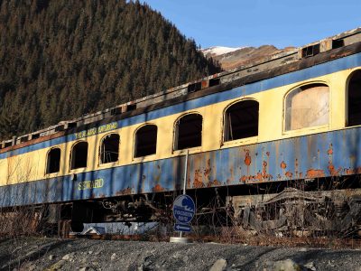 Seward, Alaska, USA - 11 05 2020: Abandoned rail car from the Alaska Railroad; rusty, broken windows, faded paint; concepts of abandoned and bygone era